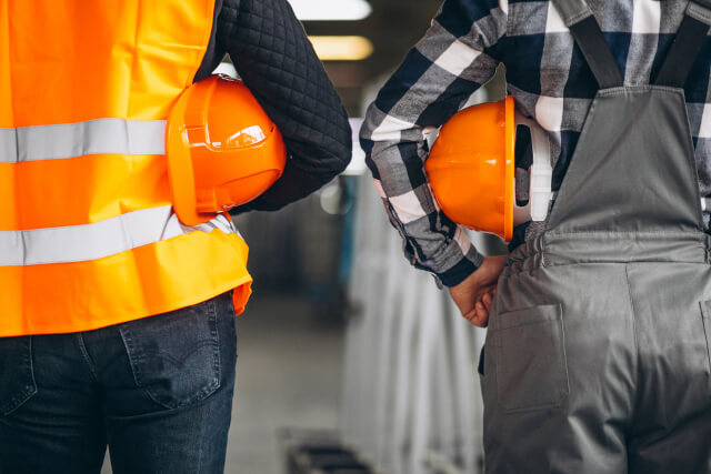 Dos trabajadores de una fábrica con cascos de seguridad en el brazo